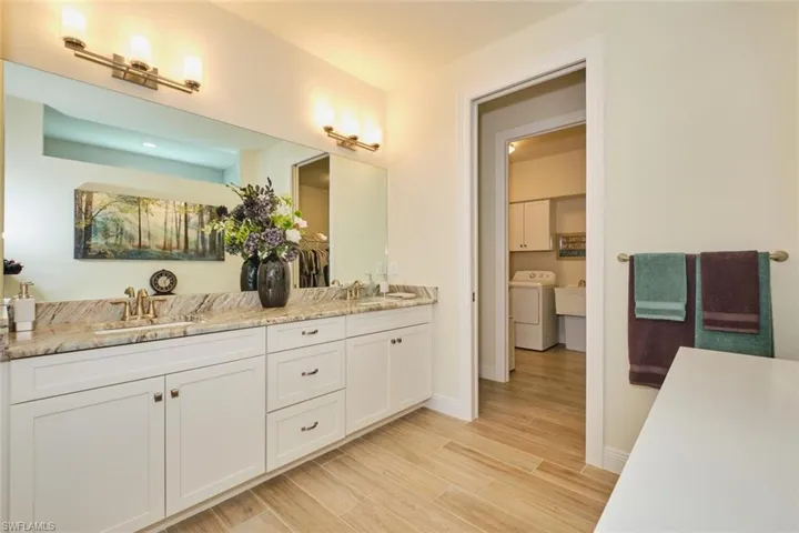 Primary Bathroom with Granite Counters, Dual Sinks,  Full width Mirror and Dual wall Lights with access to laundry room