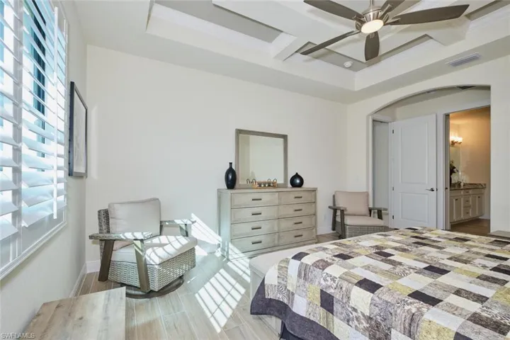Primary Bedroom featuring connected Bathroom, Plantation Shutters, Coffered ceiling, Custom molding and ceiling fan