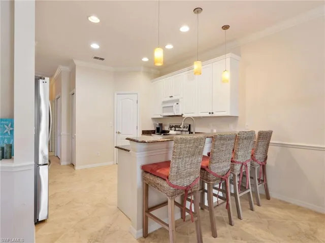 Breakfast Bar with Granite Countertop and Pendant Lighting and Crown Molding