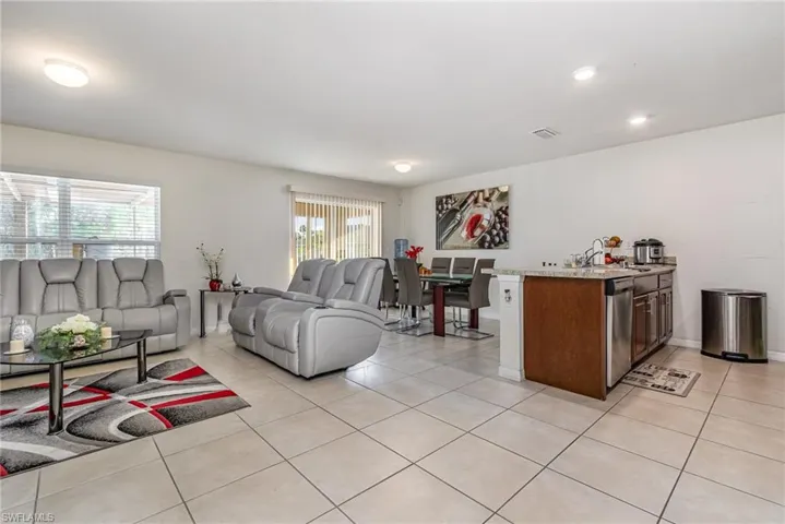 Living area with light tile patterned floors, visible vents, and baseboards