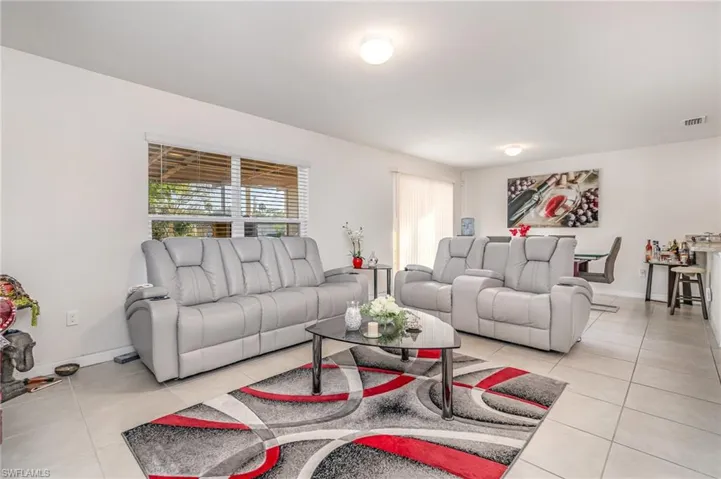 Living room with light tile patterned floors, visible vents, and baseboards