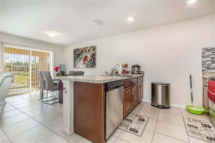 Kitchen featuring light tile patterned floors, visible vents, dishwasher, light countertops, and a sink