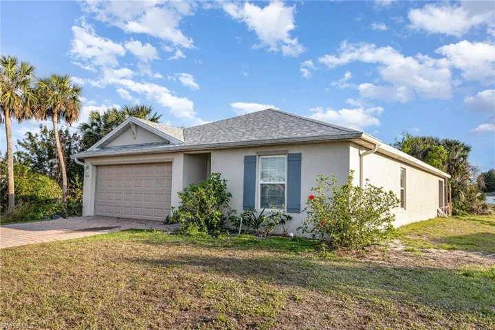 Ranch-style house with decorative driveway, stucco siding, a shingled roof, a front yard, and a garage