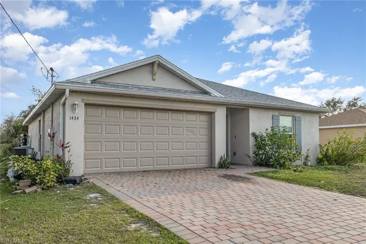 Ranch-style house featuring an attached garage, central AC unit, decorative driveway, and stucco siding