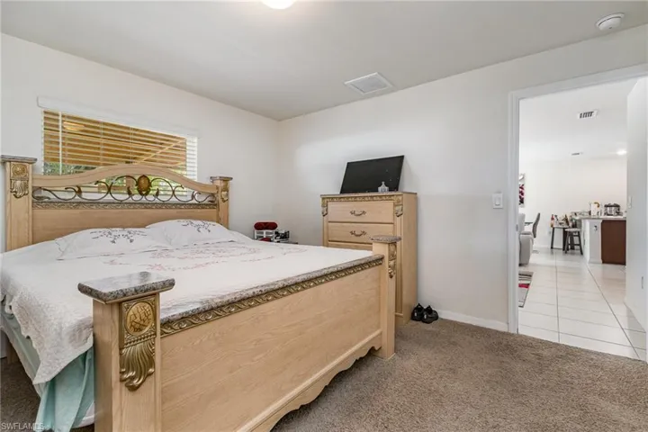 Bedroom with light carpet, light tile patterned floors, visible vents, and baseboards
