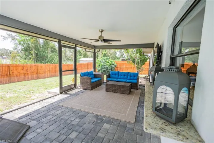 Sunroom / solarium featuring a wood stove, ceiling fan, an outdoor hangout area, and a patio area