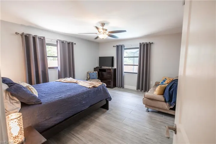 Bedroom with multiple windows, light wood-style flooring, and a ceiling fan