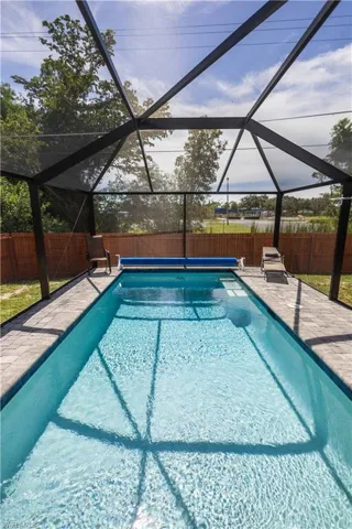 View of pool featuring a fenced backyard, glass enclosure, and a sunroom