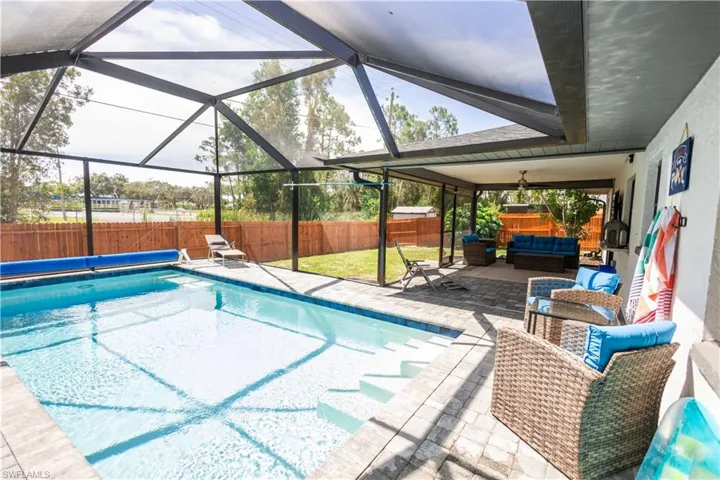 View of pool featuring a fenced backyard, an outdoor living space, a patio area, and a lanai