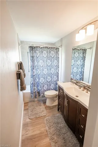 Full bath featuring vanity, light wood finished floors, and shower / bathtub combination with curtain