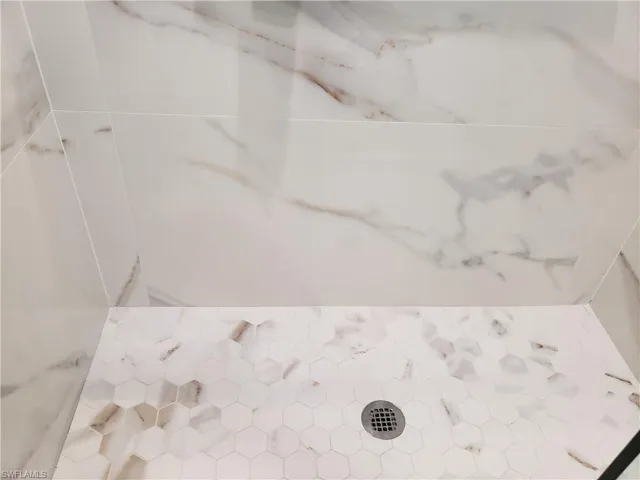 custom designed shower with large format tile on walls and custom glass and door