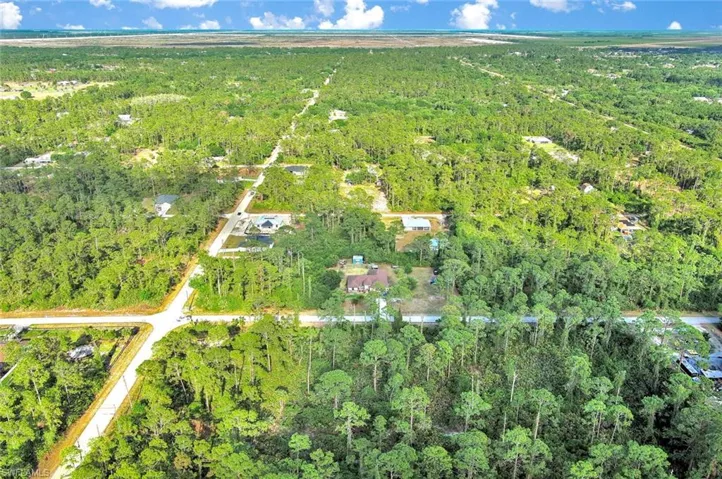 Aerial view of property and surrounding area with a forest