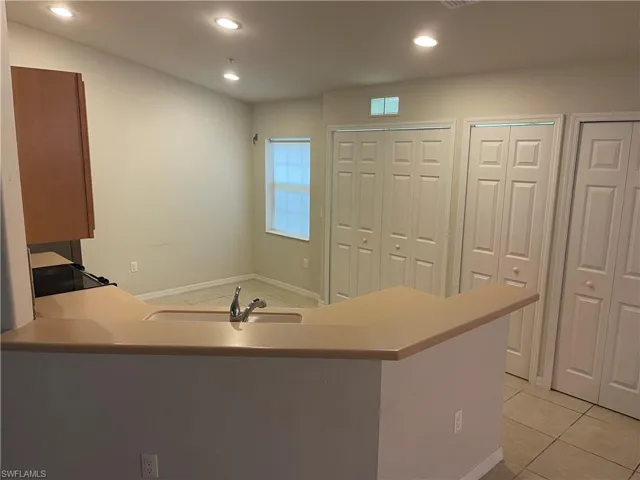 Kitchen featuring a peninsula, light countertops, light tile patterned floors, recessed lighting, and black range with electric cooktop