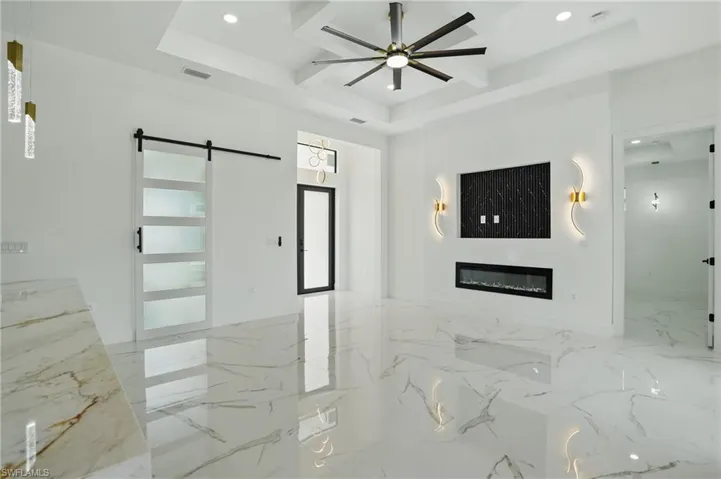 Unfurnished living room with a barn door, recessed lighting, a ceiling fan, a glass covered fireplace, and marble finish flooring