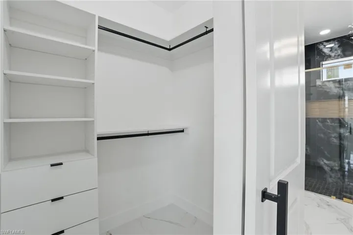 Walk in closet featuring marble finish flooring