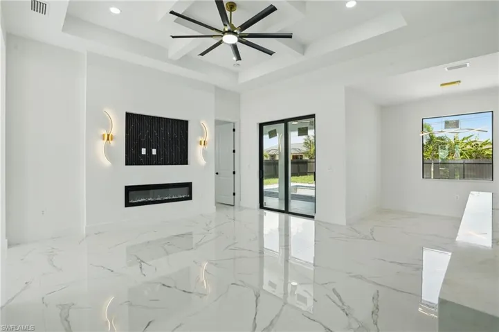 Unfurnished living room featuring plenty of natural light, recessed lighting, baseboards, a glass covered fireplace, and marble tiled floors