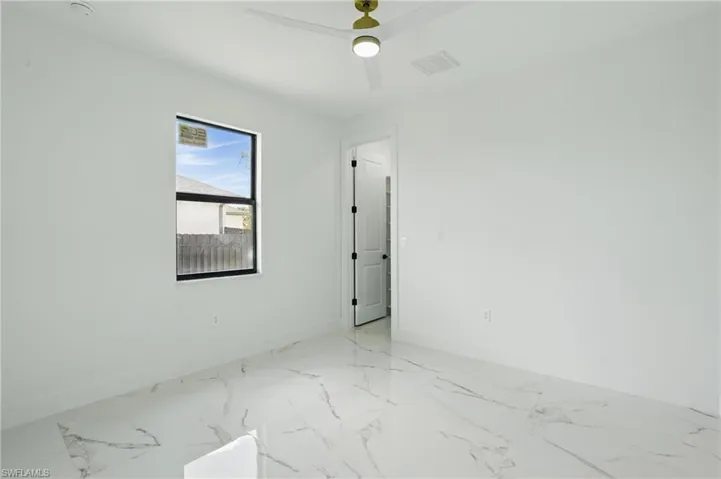 Empty room featuring baseboards, light marble finish flooring, and ceiling fan