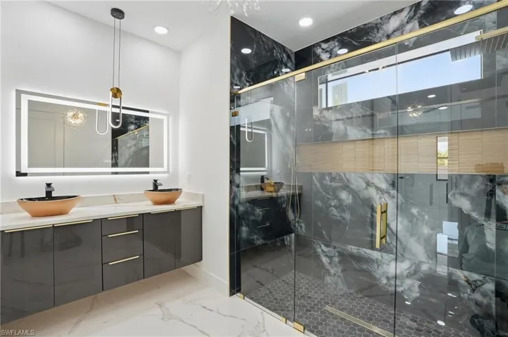 Bathroom featuring marble tiled floors, double vanity, a marble finish shower, recessed lighting, and baseboards