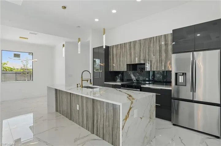 Kitchen featuring stainless steel fridge, modern cabinets, a sink, electric stove, and light marble finish floors