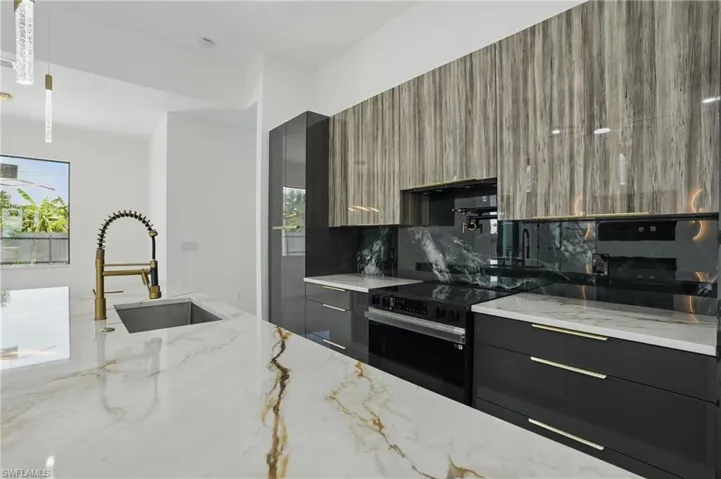 Kitchen featuring modern cabinets, black / electric stove, a sink, light stone countertops, and ventilation hood