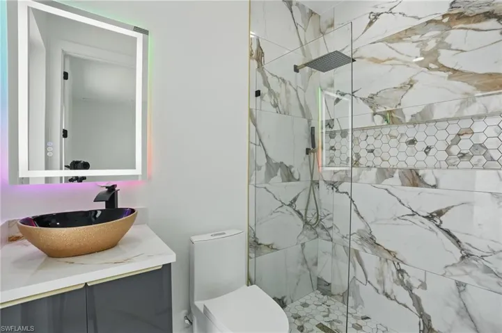 Bathroom with a marble finish shower, vanity, and toilet