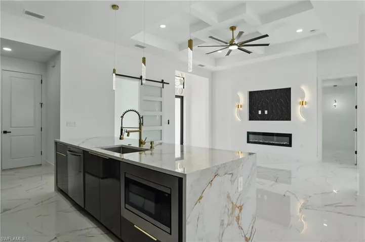 Kitchen with a sink, modern cabinets, stainless steel appliances, open floor plan, and a barn door