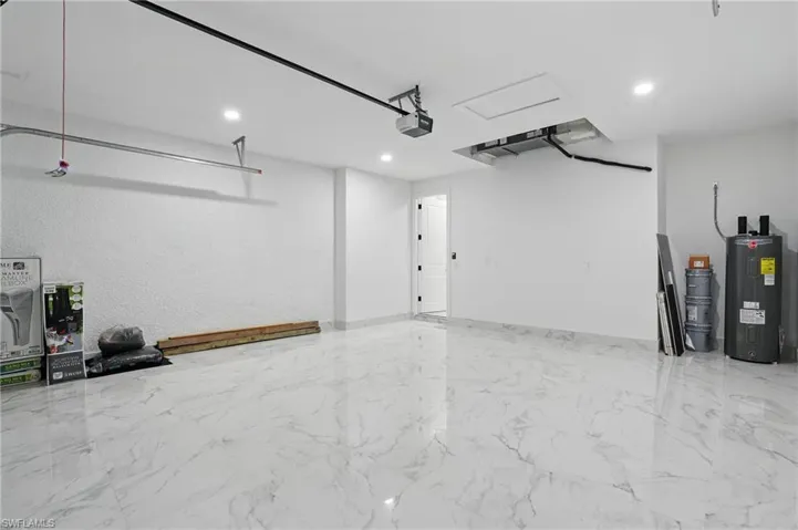 Garage featuring water heater, a garage door opener, and recessed lighting