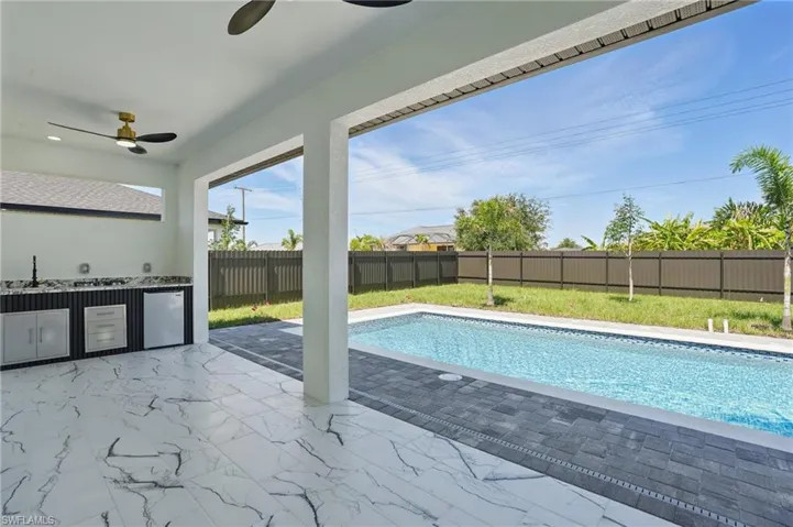 View of swimming pool with area for grilling, ceiling fan, a fenced backyard, a sink, and a patio area
