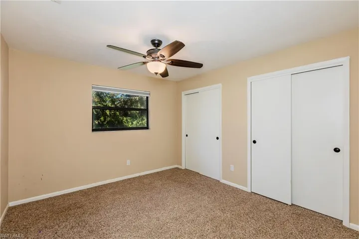 Unfurnished bedroom with carpet flooring, ceiling fan, and multiple closets
