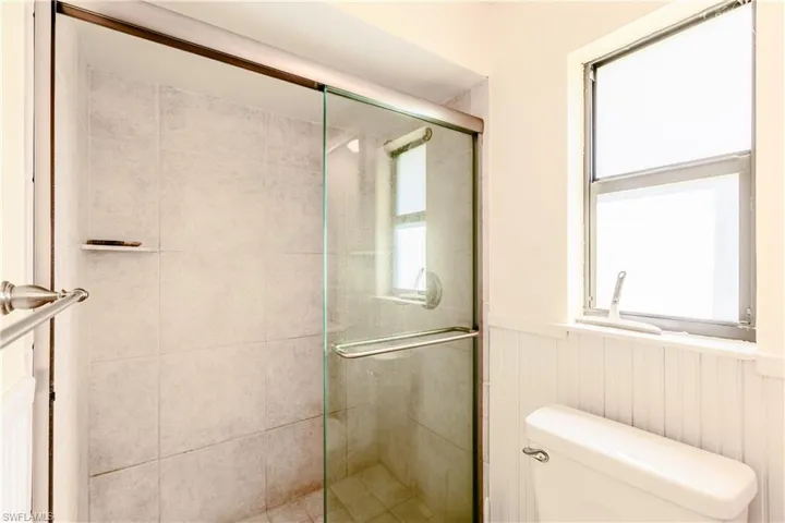 Bathroom with plenty of natural light, a shower with shower door, and toilet
