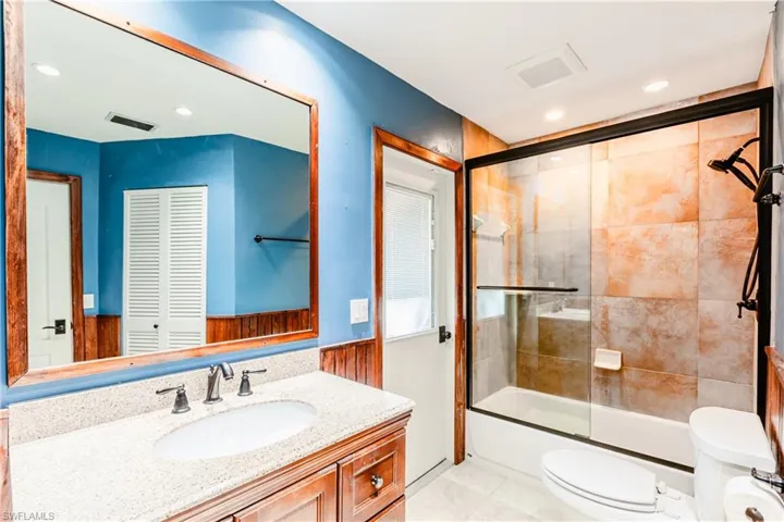 Full bathroom featuring vanity, toilet, and enclosed tub / shower combo