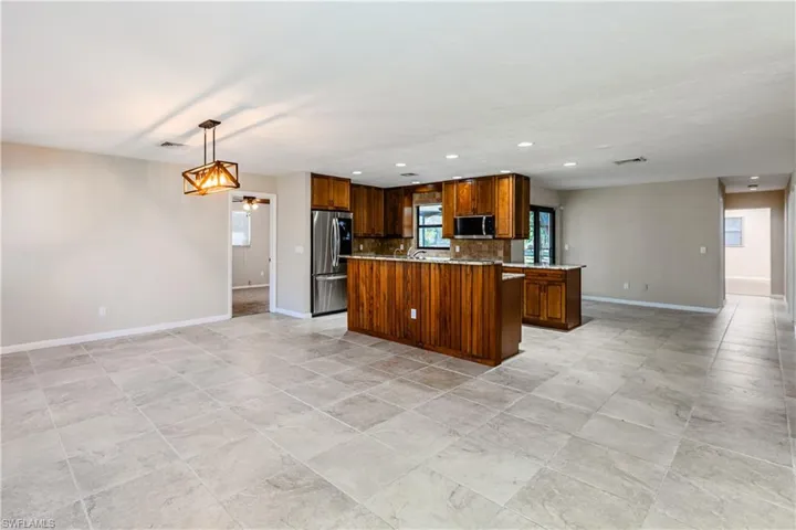 Kitchen featuring a center island, hanging light fixtures, ceiling fan, appliances with stainless steel finishes, and tasteful backsplash
