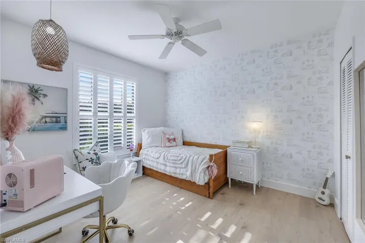 Bedroom with light wood-type flooring, ceiling fan, and a closet