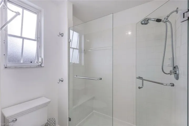 Bathroom featuring a shower with shower door and toilet