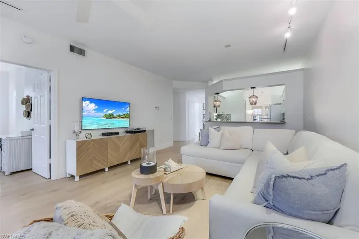 Living room with light wood-type flooring and track lighting