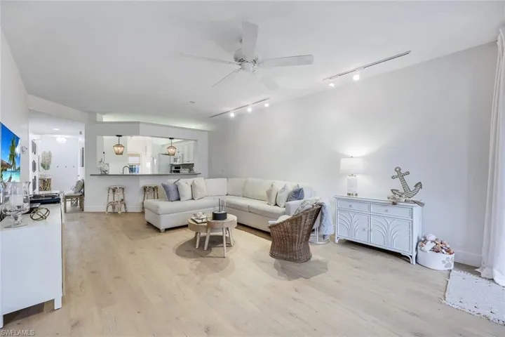 Living room with rail lighting, light wood-type flooring, and ceiling fan