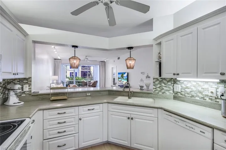 Kitchen with decorative backsplash, pendant lighting, white dishwasher, and sink