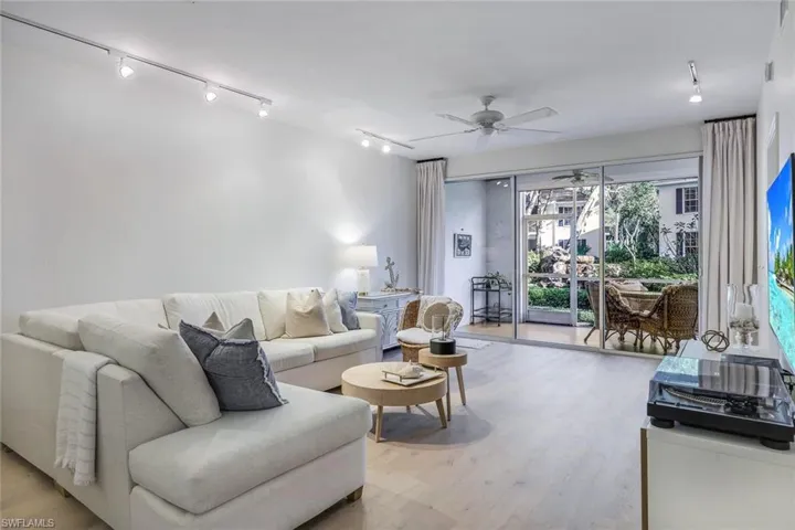 Living room with light hardwood / wood-style flooring, ceiling fan, and track lighting