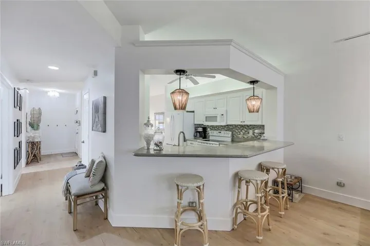Kitchen featuring white cabinetry, white appliances, ceiling fan, light hardwood / wood-style floors, and pendant lighting