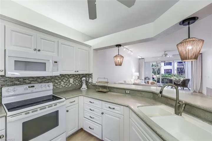 Kitchen with decorative backsplash, pendant lighting, white appliances, and ceiling fan