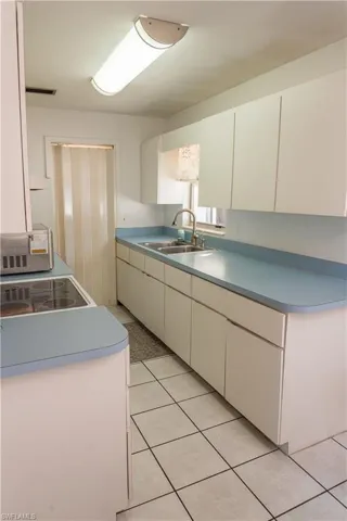 Kitchen with white cabinets, light countertops, electric stove, and light tile patterned flooring