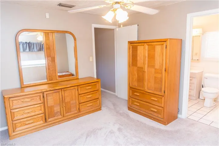 Bedroom featuring light carpet, connected bathroom, a ceiling fan, and light tile patterned floors