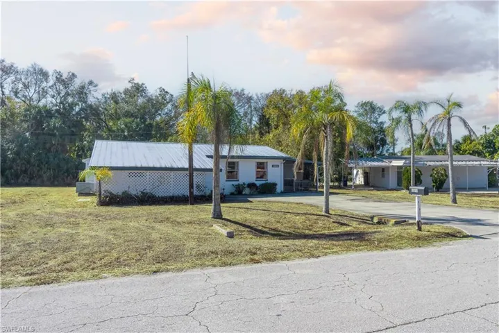 Ranch-style house featuring a front yard, concrete driveway, and a metal roof