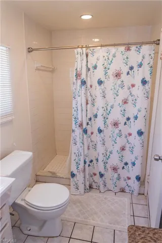 Bathroom with vanity, light tile patterned flooring, a tile shower, and recessed lighting