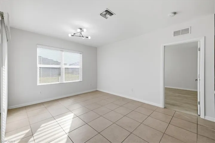 Neutral-toned tile flooring, white walls, and a multi-bulb ceiling fixture
