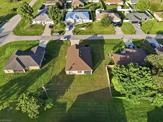 Expansive property featuring a brown shingle roof, light-colored exterior walls, a screened-in patio, and a spacious green lawn