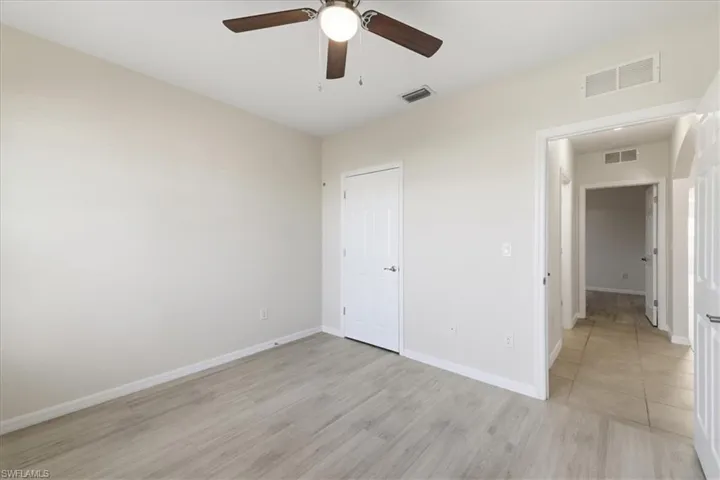 Light wood-finish flooring, neutral wall tones, and a ceiling fan with integrated lighting