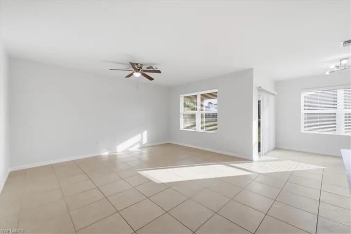 Spacious room featuring tile flooring, multiple windows with blinds, a ceiling fan, and track lighting