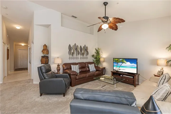 Carpeted living area with a ceiling fan, baseboards, and visible vents