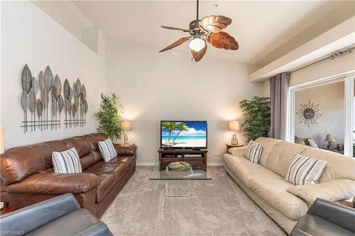 Living room with baseboards, ceiling fan, and carpet